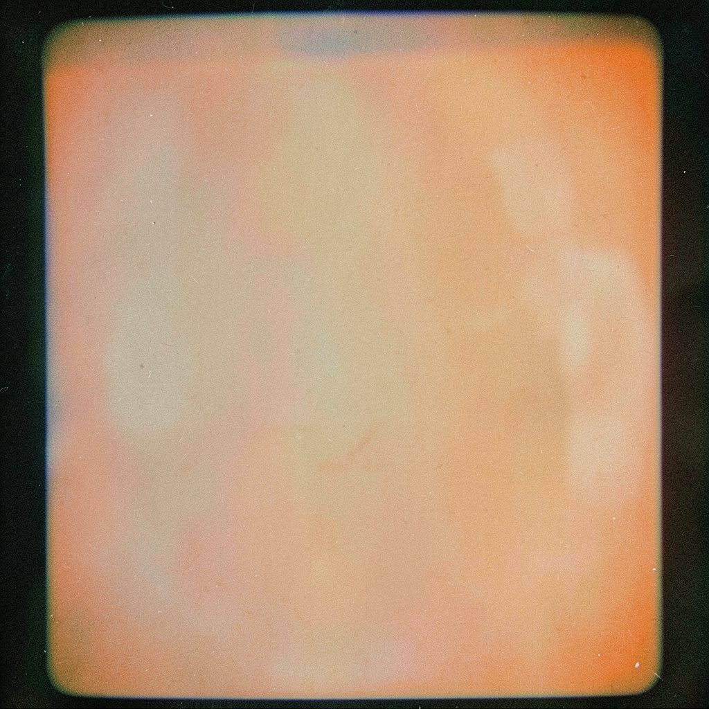 A grainy black and white film photograph of a vintage reel-to-reel film camera on a tripod, warm amber tones, nostalgic documentary mood